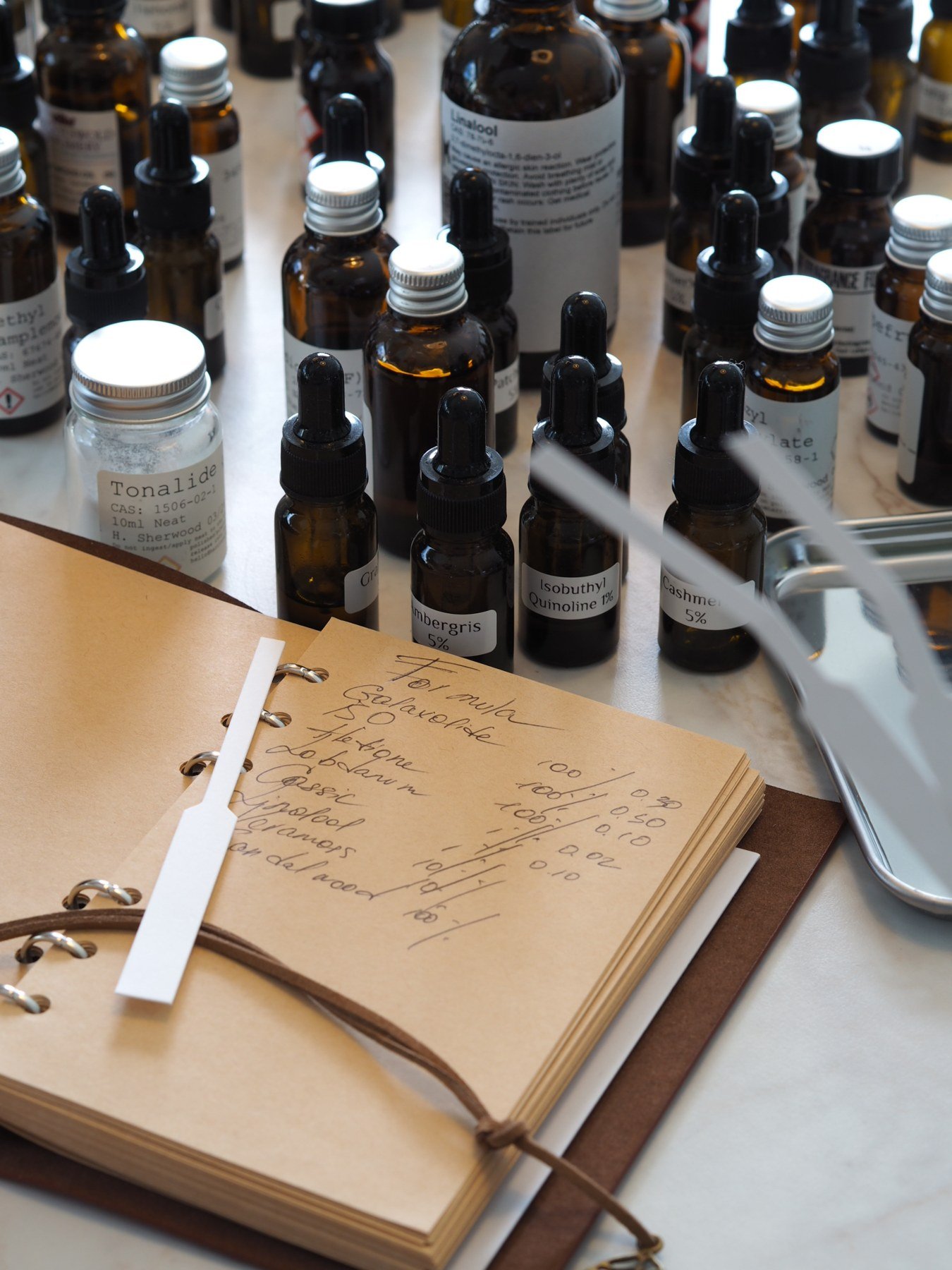 A handwritten perfume formula and amber ingredient bottles