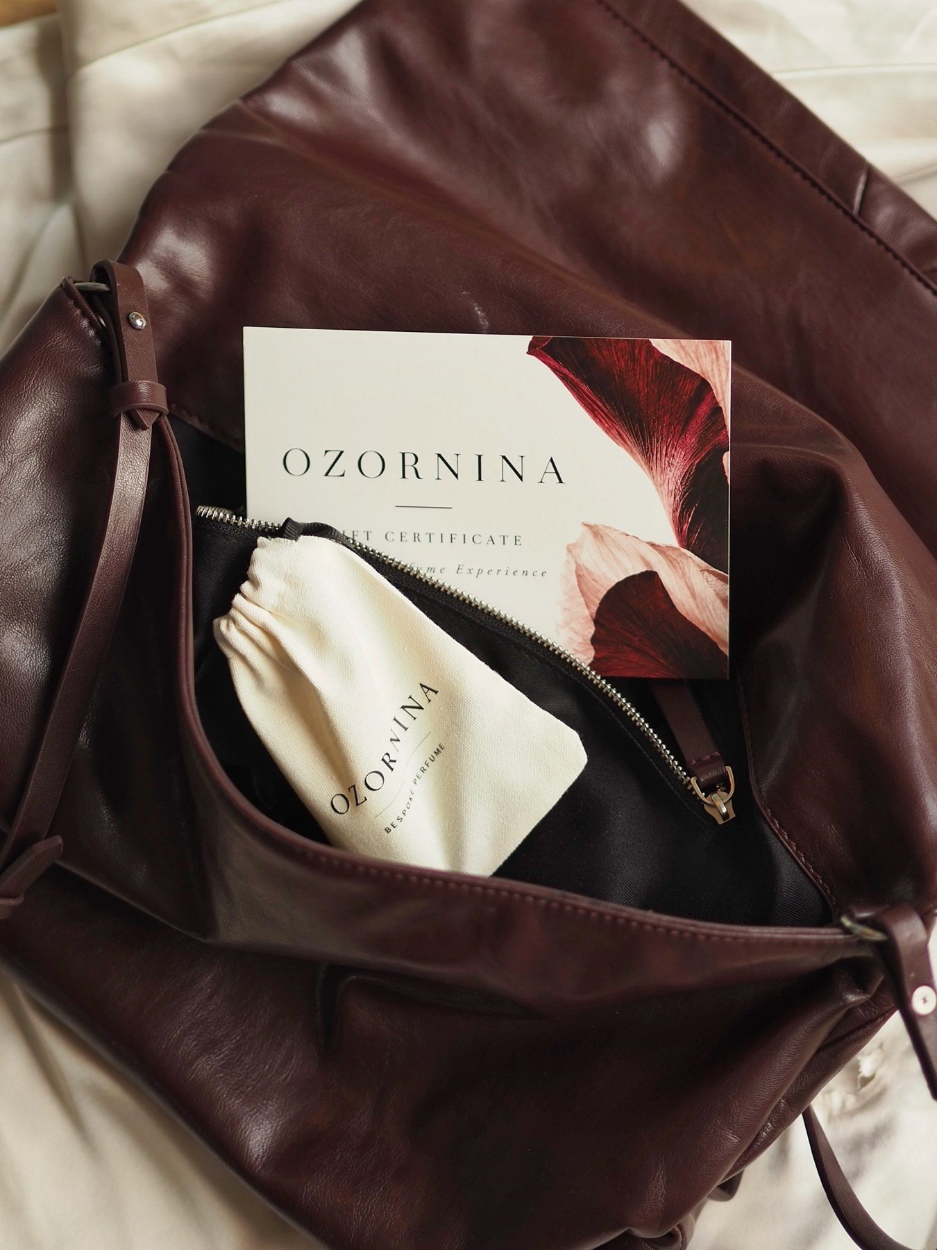 Gift certificate and OZORNINA cotton pouch tucked into a leather bag